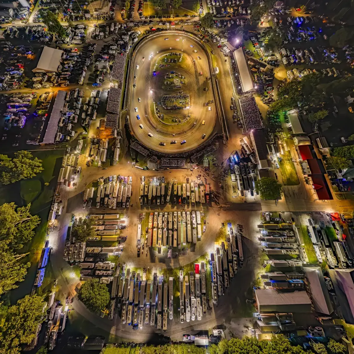 Top-down aerial drone photo of Fairbury Speedway dirt track racing at night surrounded by campgrounds