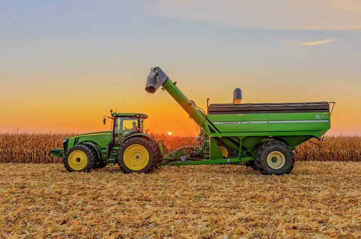 John Deere tractor and grain cart in a harvested cornfield at sunset, agricultural photography Central Illinois